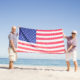 two seniors holding an American flag on the beach.