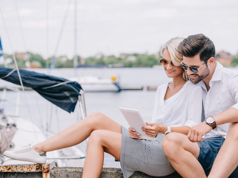 couple in a marina looking at a tablet